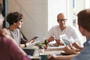 a group of people sit around a table in a bright office