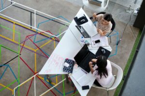 a group of people working on laptops around a desk, from overhead.